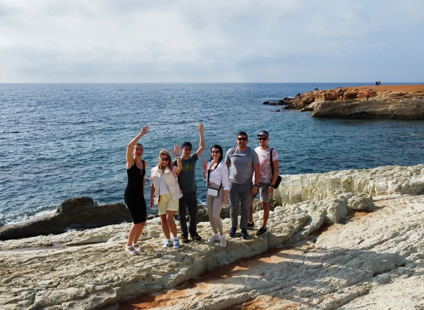 VL team waving on a rocky seashore
